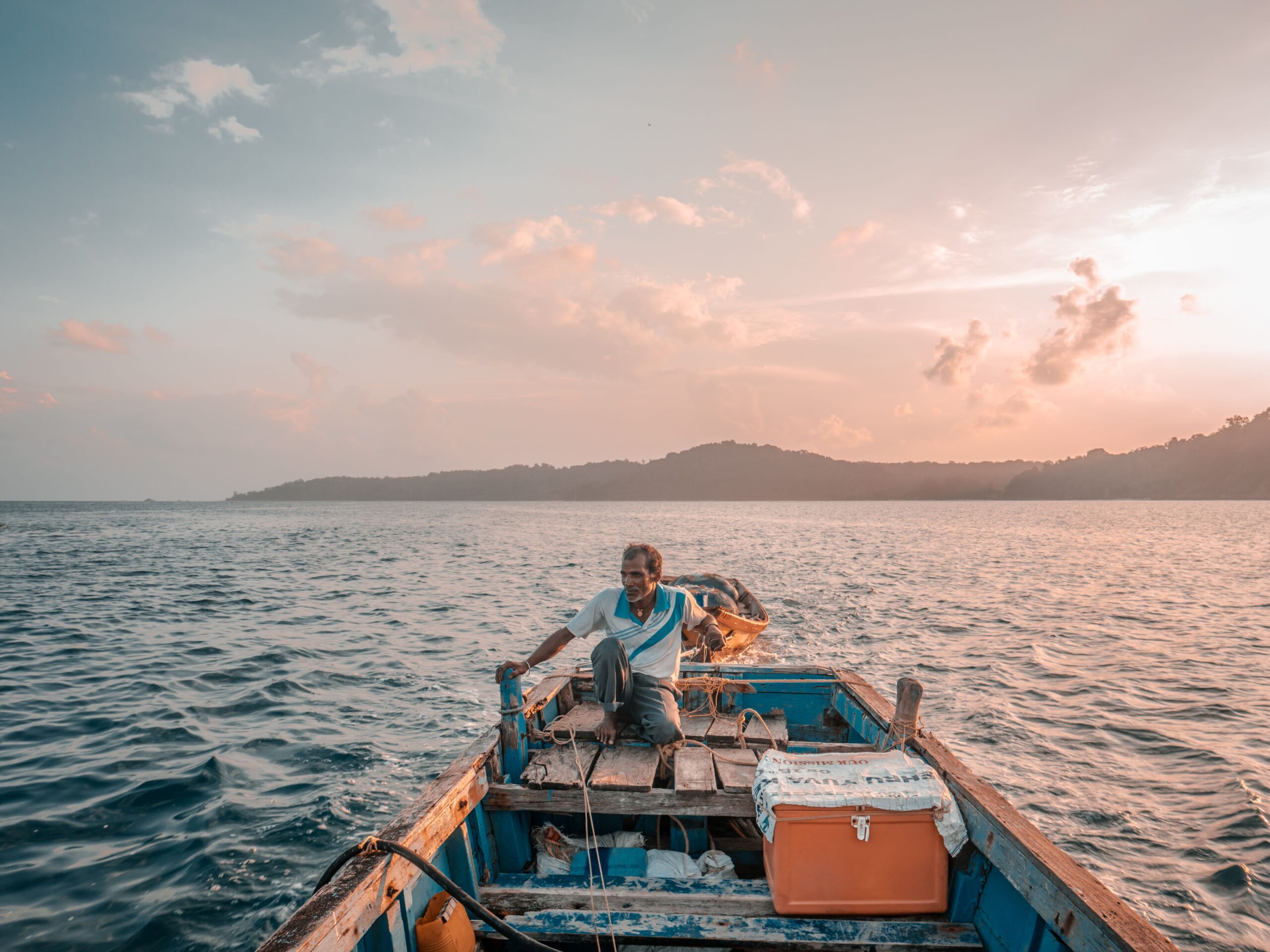 A lone fisherman navigates the calm waters of the Andaman Sea at sunrise, setting out for a day of adventure.