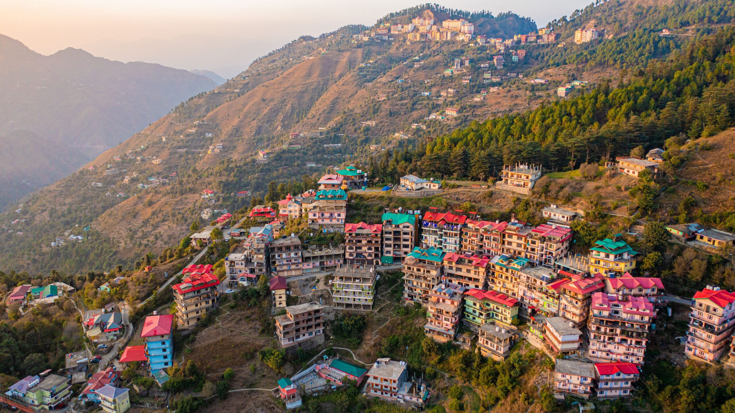 Aerial view of colorful houses on a Shimla hillside at sunrise, Himachal Pradesh.
