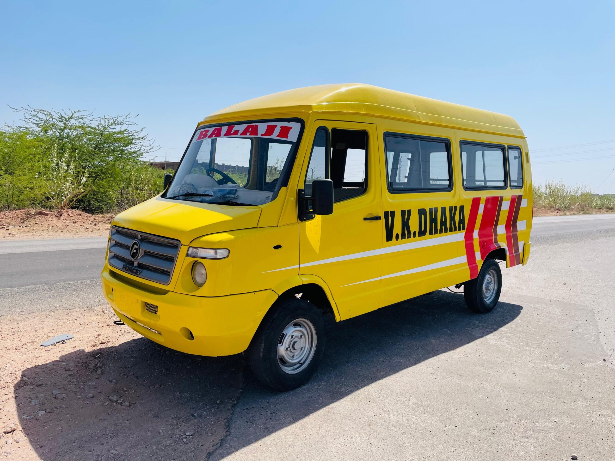 A vivid yellow passenger van parked on a sunny rural roadside, perfect for travel-related themes.