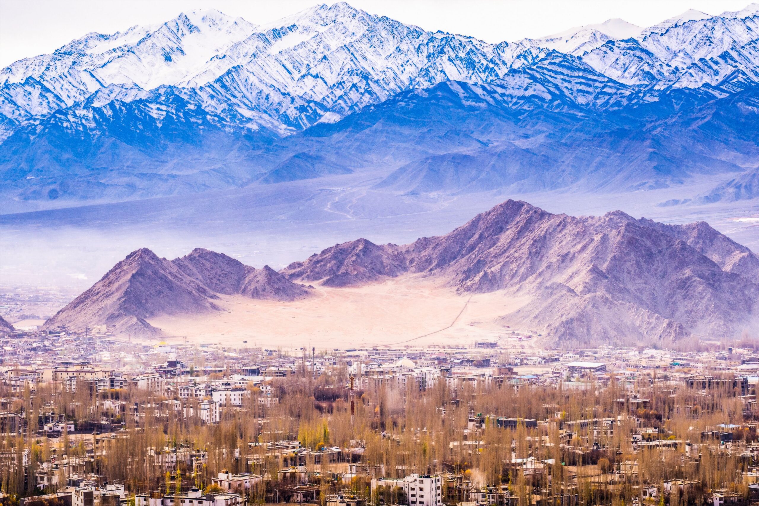 Breathtaking aerial view of Leh in Ladakh, India, surrounded by majestic snow-capped mountains.